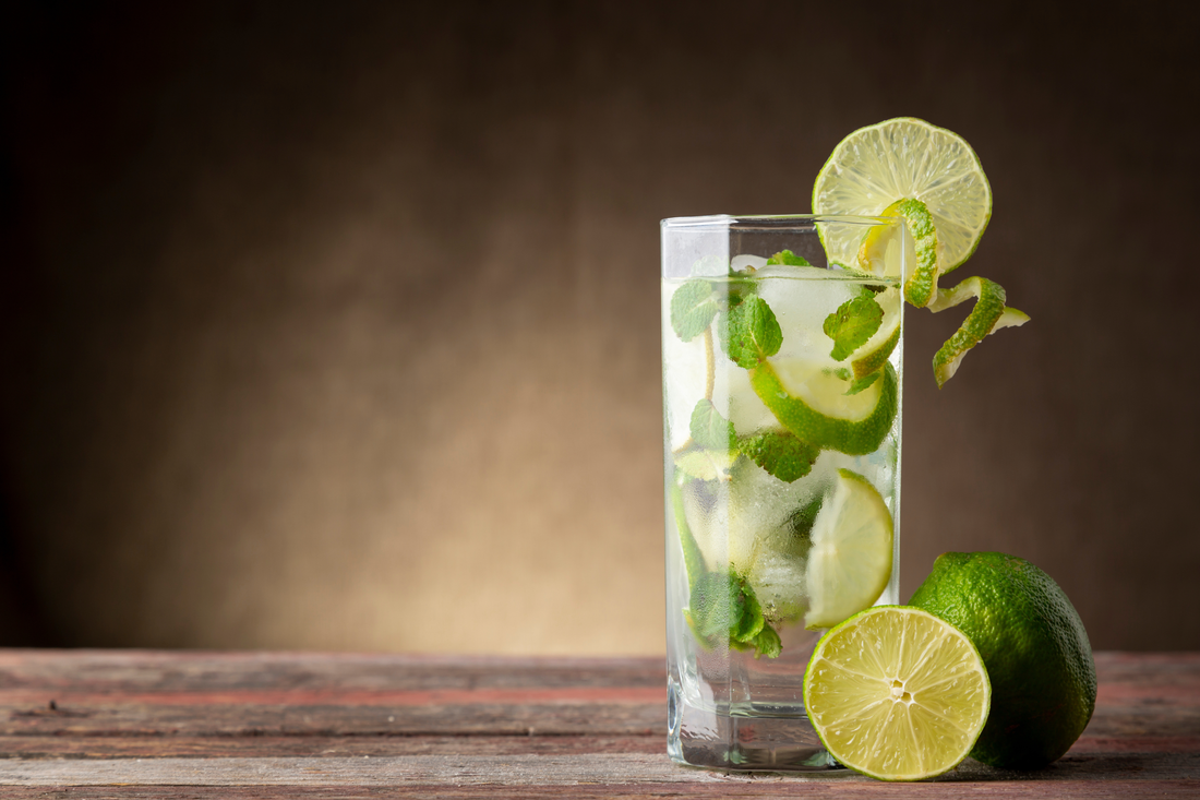 tall glass of Virgin Mojito with lime and mint beside two limes