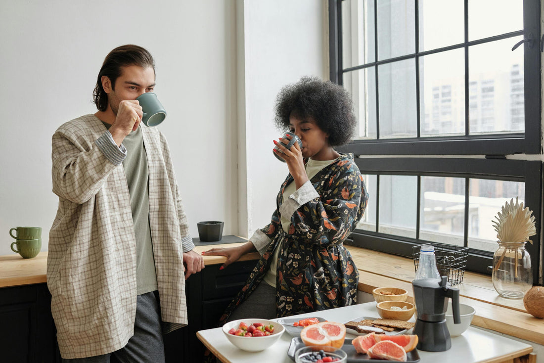 a couple standing in their kitchen, each drinking a cup of alternatives to alcohol to relax