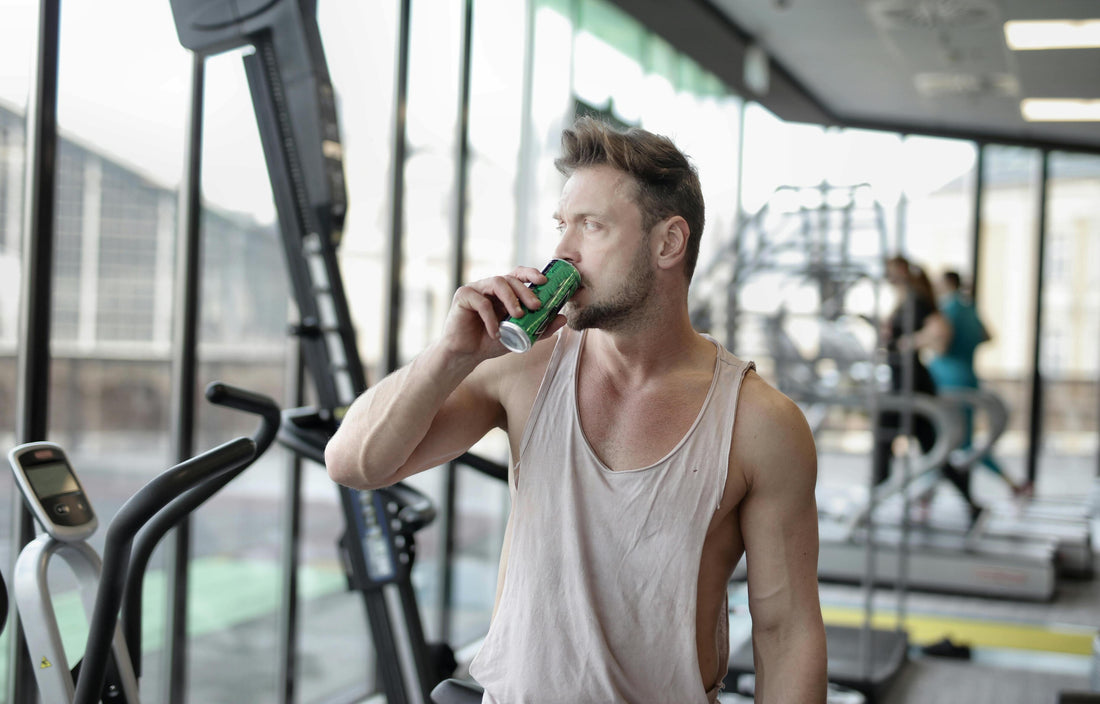 white man in a gym sipping a recovery workout drink from a can