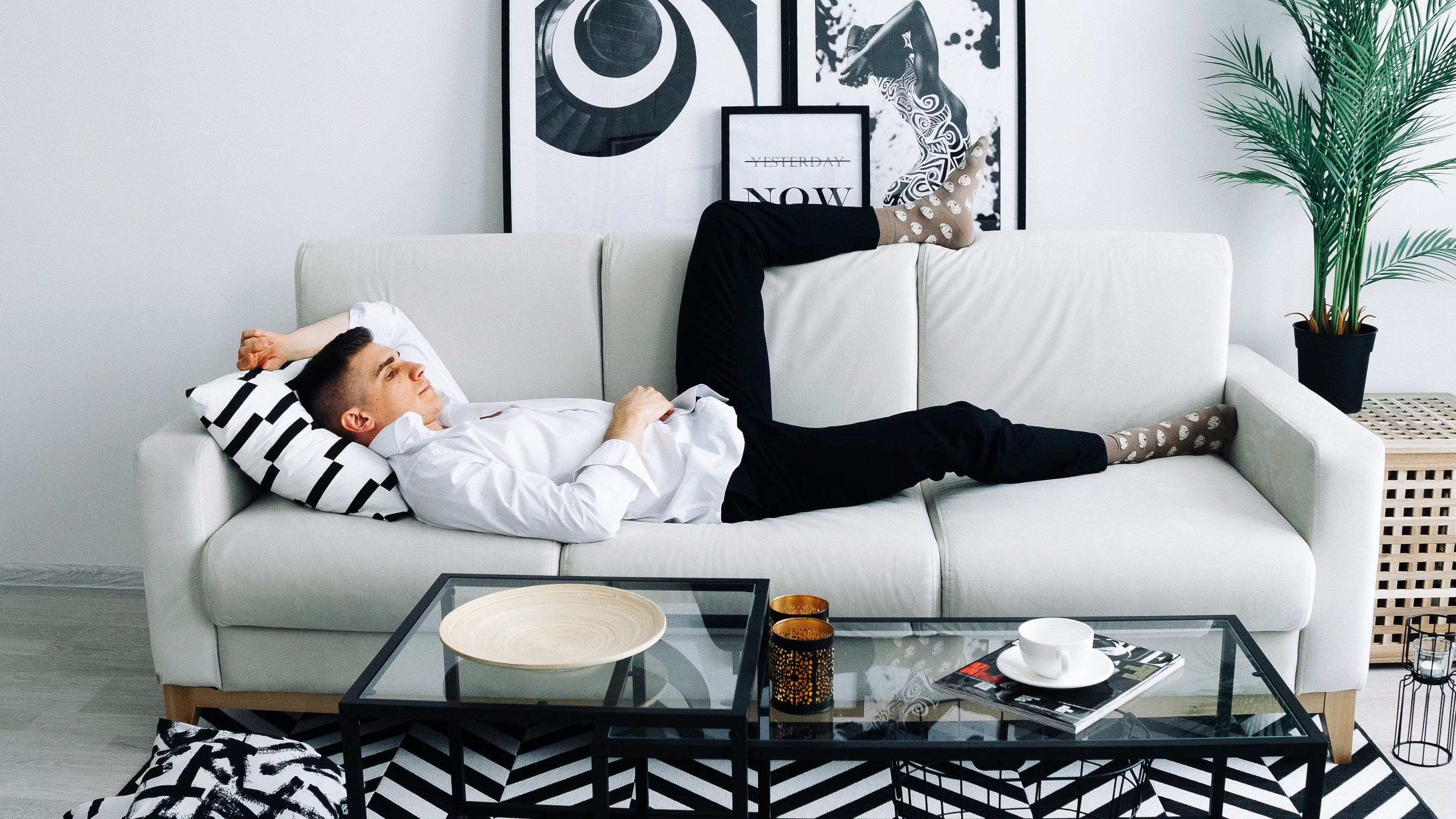 man on a THC drink detox lying on a white sofa behind a coffee table to come down from a THC high