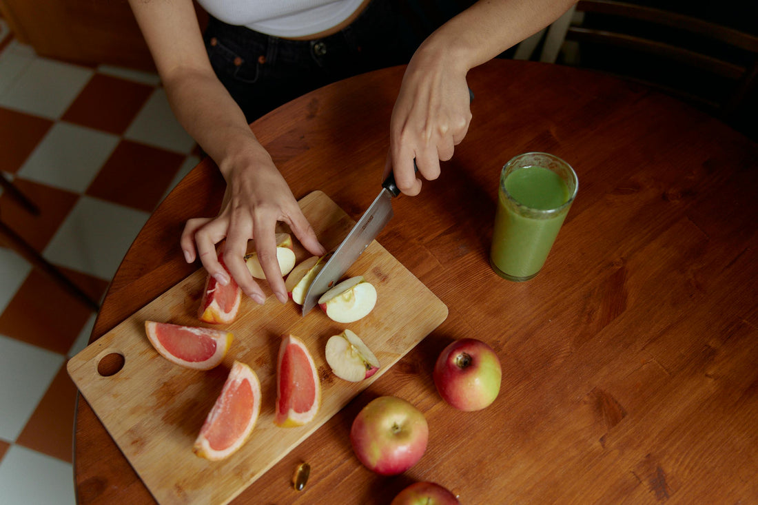 woman’s hands slicing fruits on a chopping board beside a keto-friendly drink and 2 apples